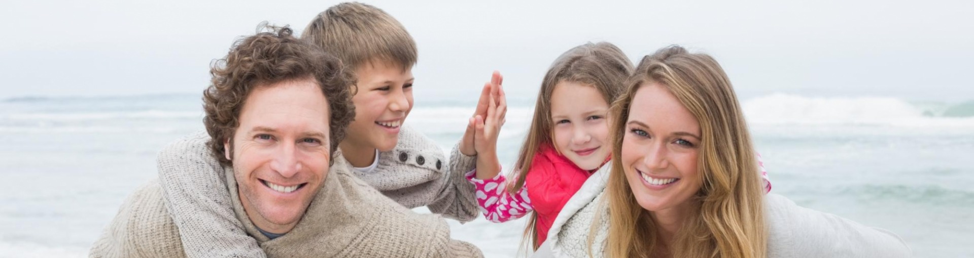 Gezin op het strand ouders met kinderen op hun rug